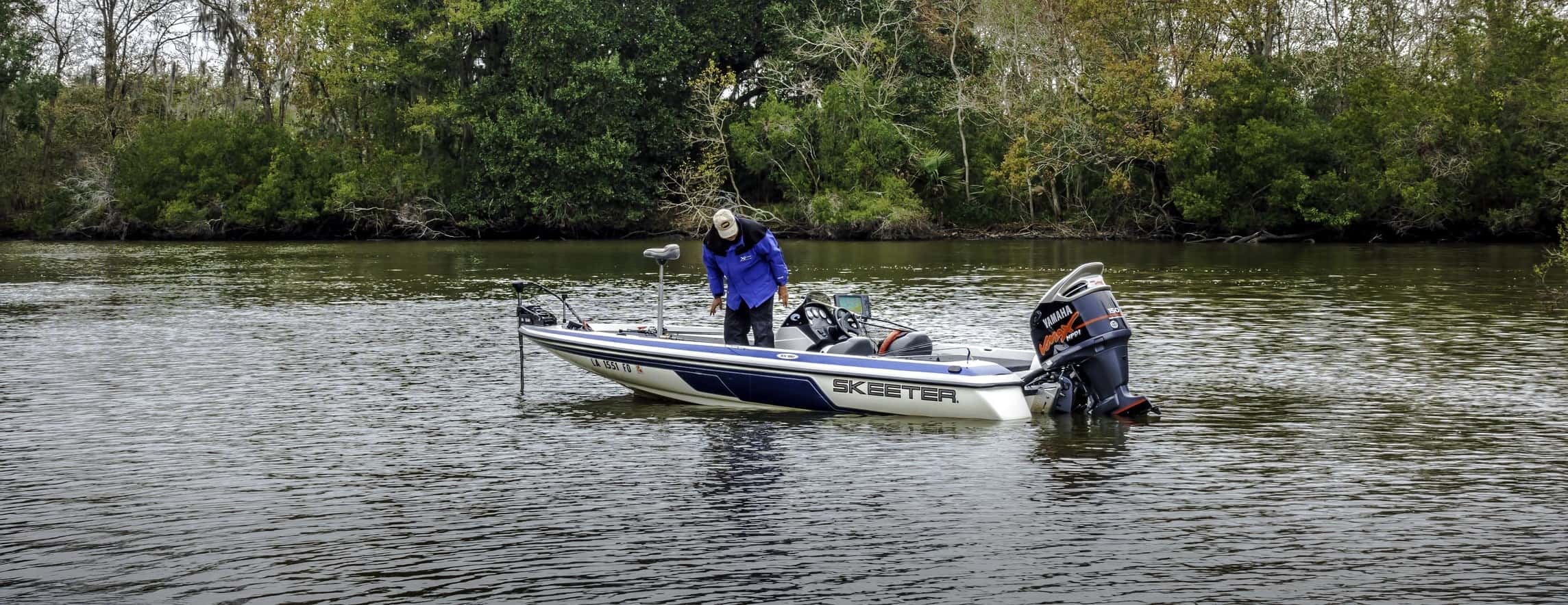 A man takes a small boat on a river while fishing in Louisiana