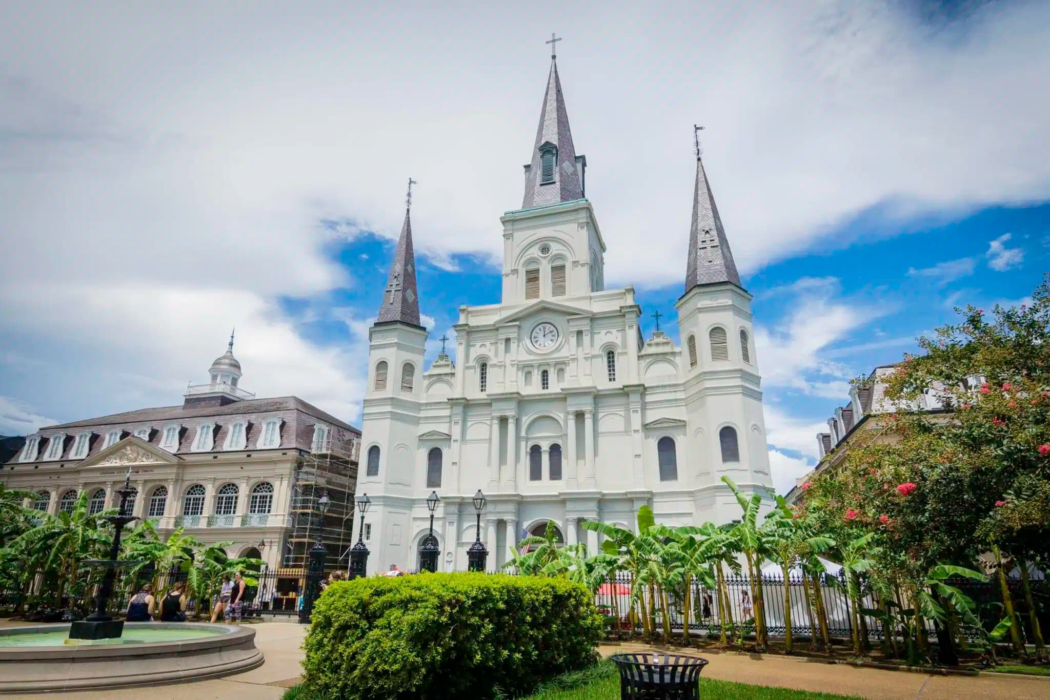 St. Louis Cathedral with its iconic spires in Jackson Square, New Orleans, under a bright blue sky.