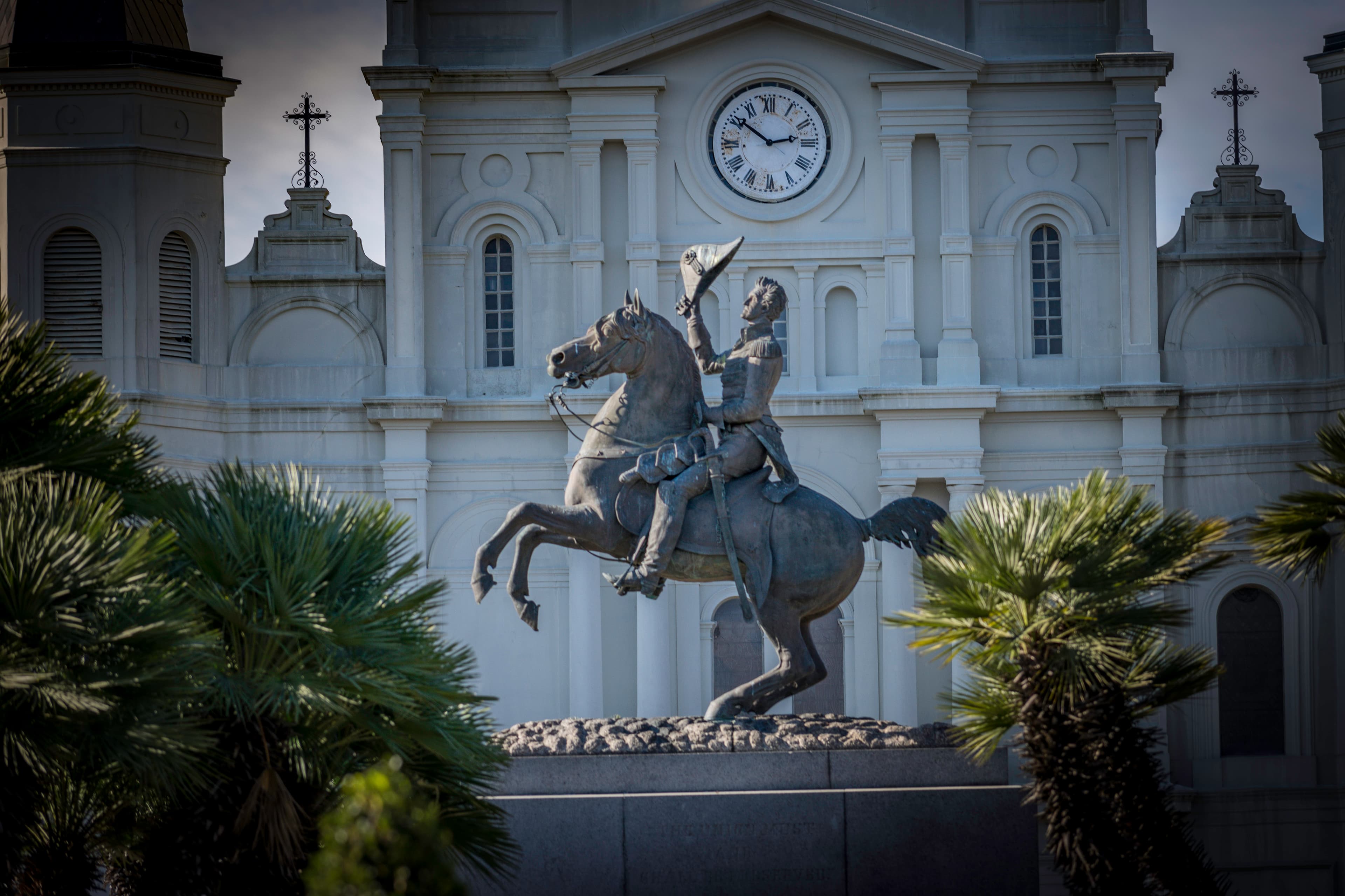 Statue of Andrew Jackson on horseback in front of St. Louis Cathedral in New Orleans, framed by palm trees.