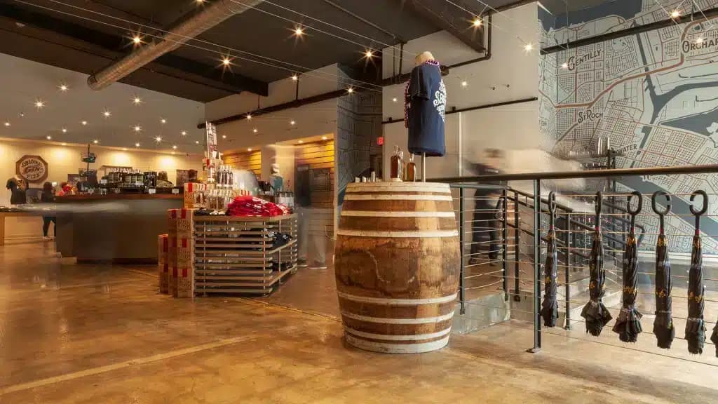 A modern gift shop with a barrel display, merchandise racks holding clothing and souvenirs, a large map on the wall, and bright overhead lighting in a polished industrial-style space.