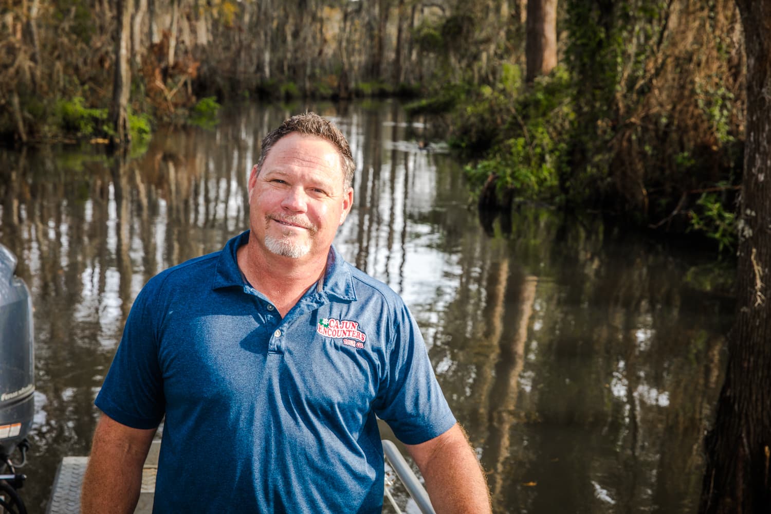 jeff rogers, owner of cajun encounters, standing in front of a cajun encounters tour boat in the honey island swamp