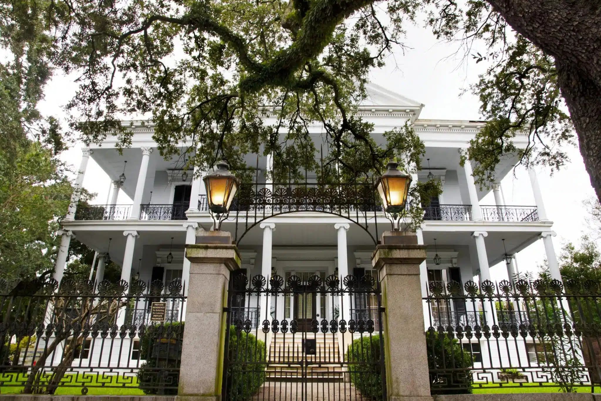 a frontal view of a beautiful white mansion in the garden district