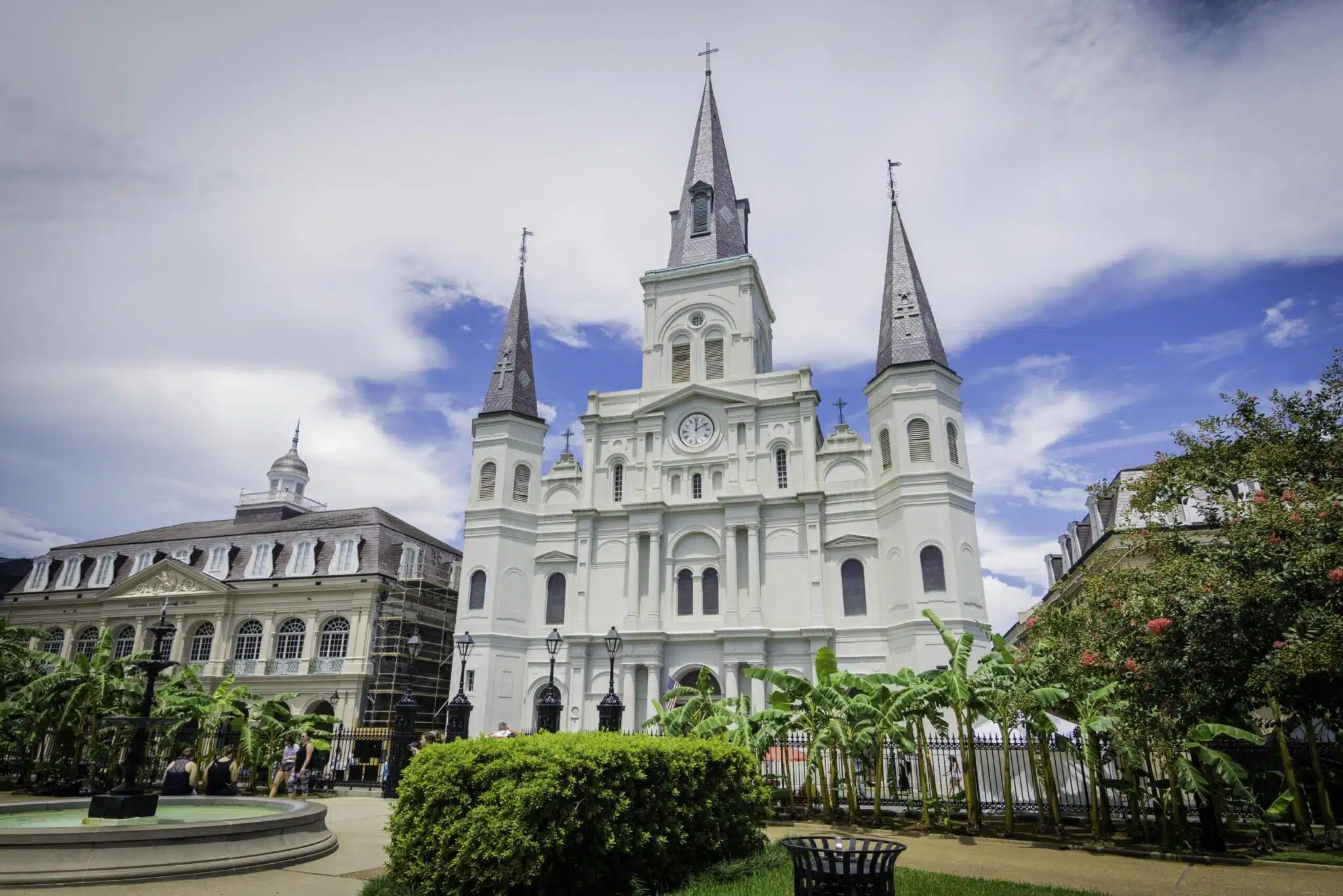 St. Louis Cathedral with its iconic spires in Jackson Square, New Orleans, under a bright blue sky.