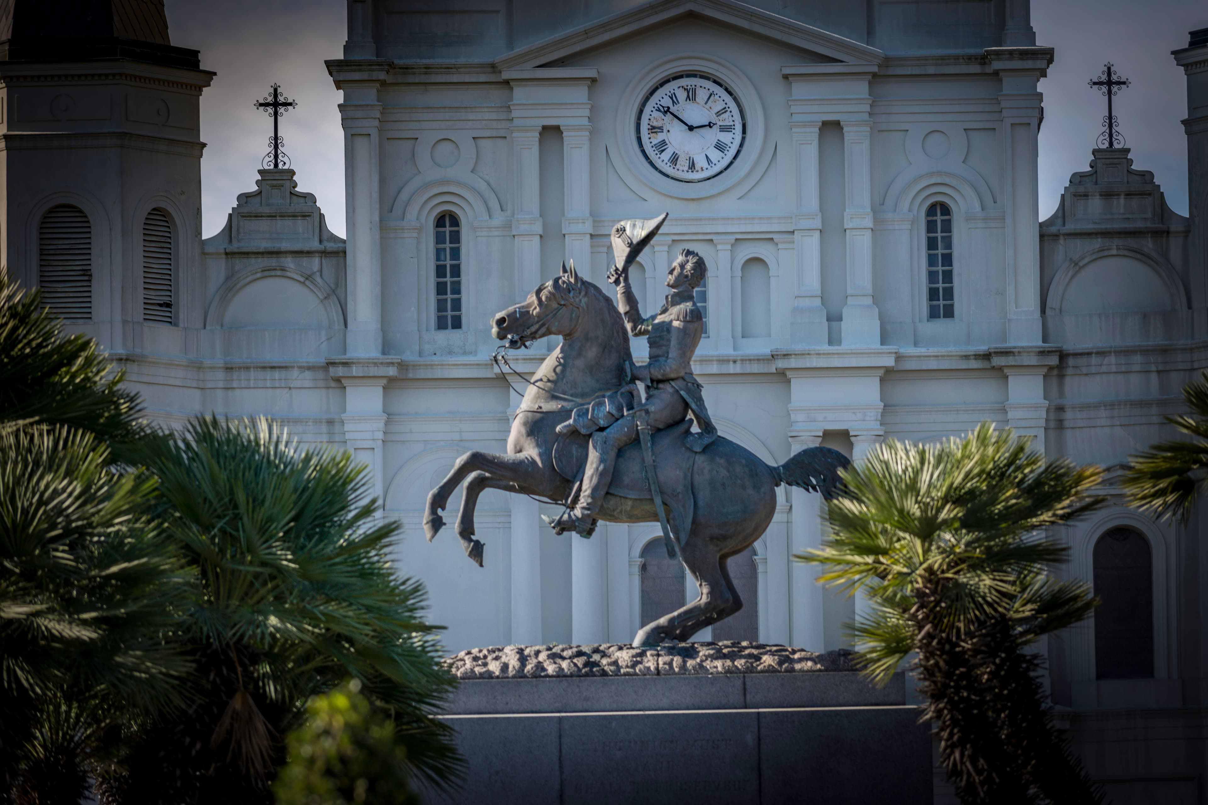 Equestrian statue of Andrew Jackson in front of St. Louis Cathedral, framed by palm trees in Jackson Square, New Orleans.
